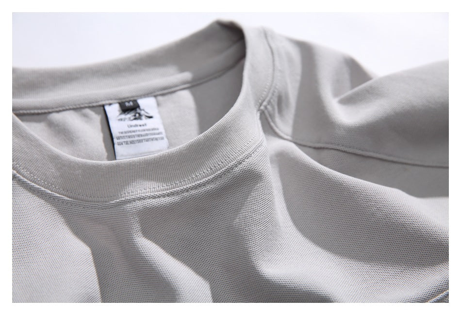 Close-up of a light gray shirt's ribbed crew neckline and sewn-in neck label.