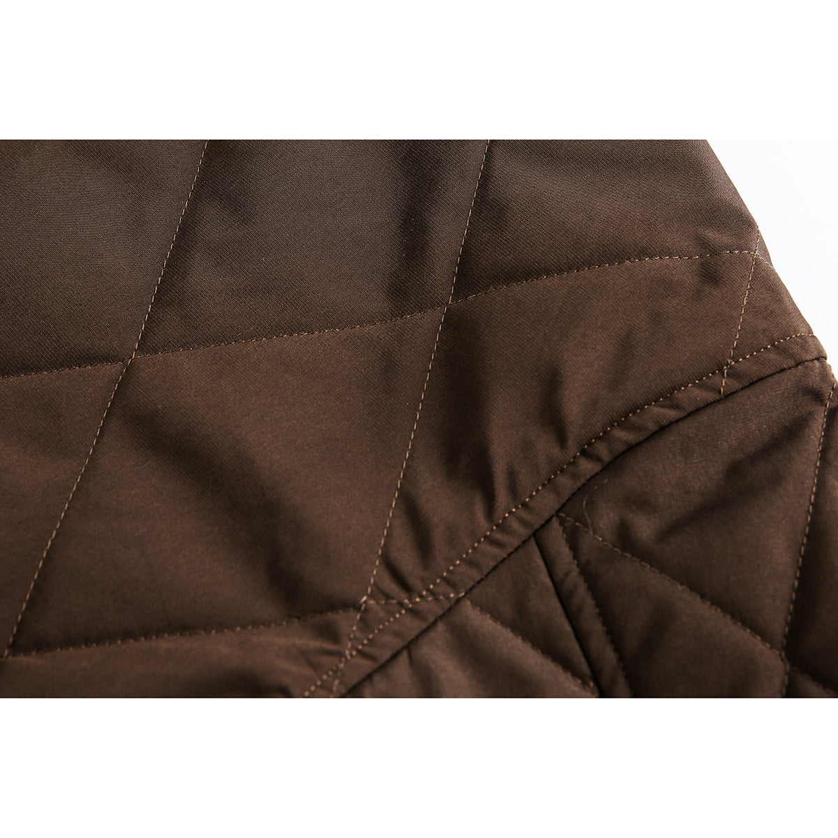 Close-up of dark brown quilted jacket fabric and stitched seams.