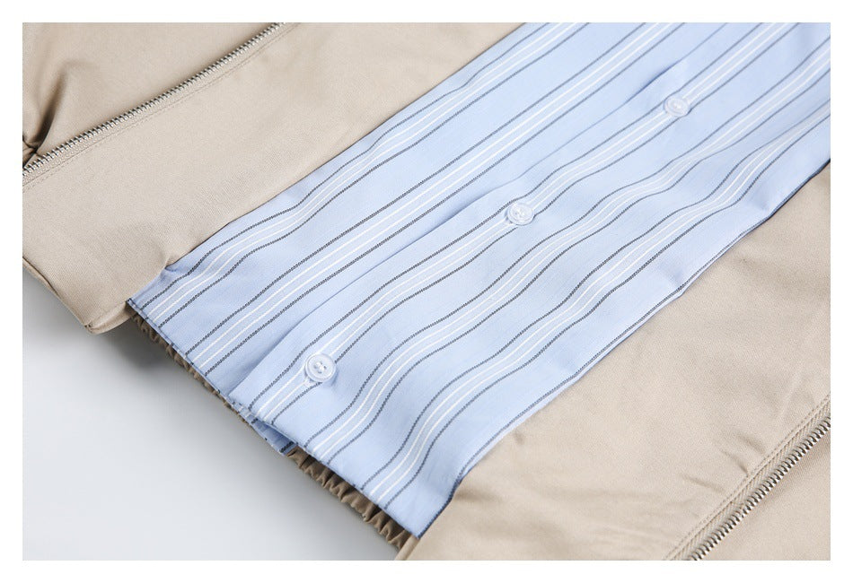 Close-up of the jacket's light blue striped button-front panel between beige zipper edges.