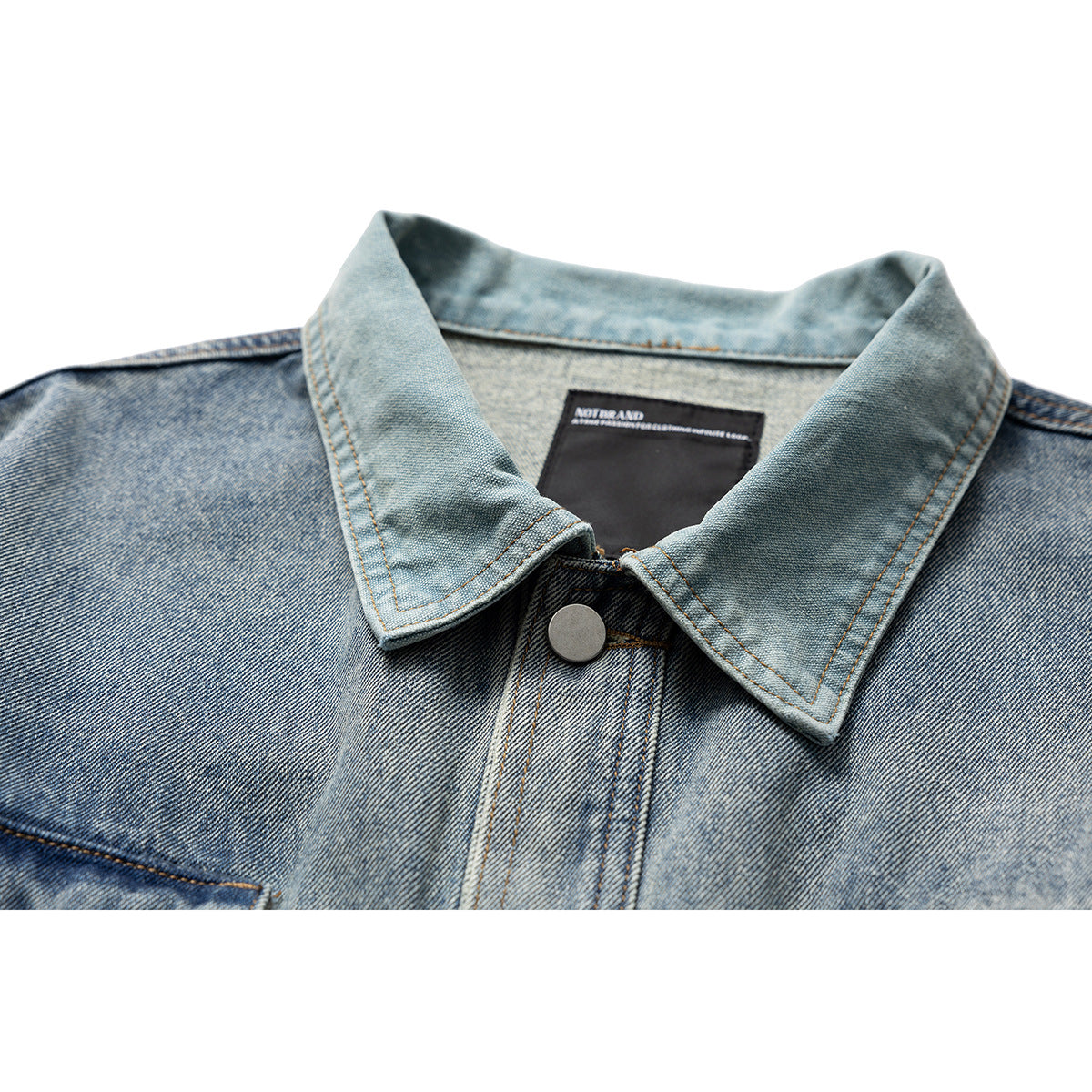 Close-up of a light blue denim jacket collar, button, topstitching, and inner neck label.