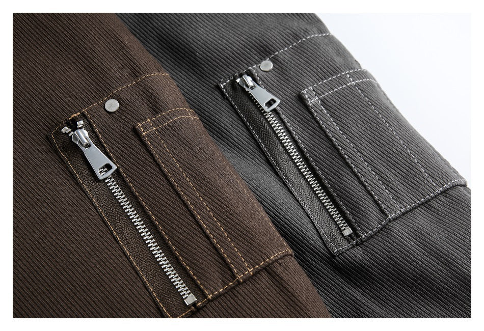 Close-up of brown and charcoal ribbed jacket panels with zip pockets, metal snaps, and contrasting stitching.