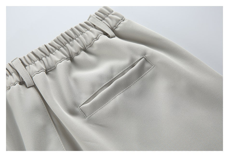 Close-up of a slanted pocket and elasticated waistband on light beige trousers.