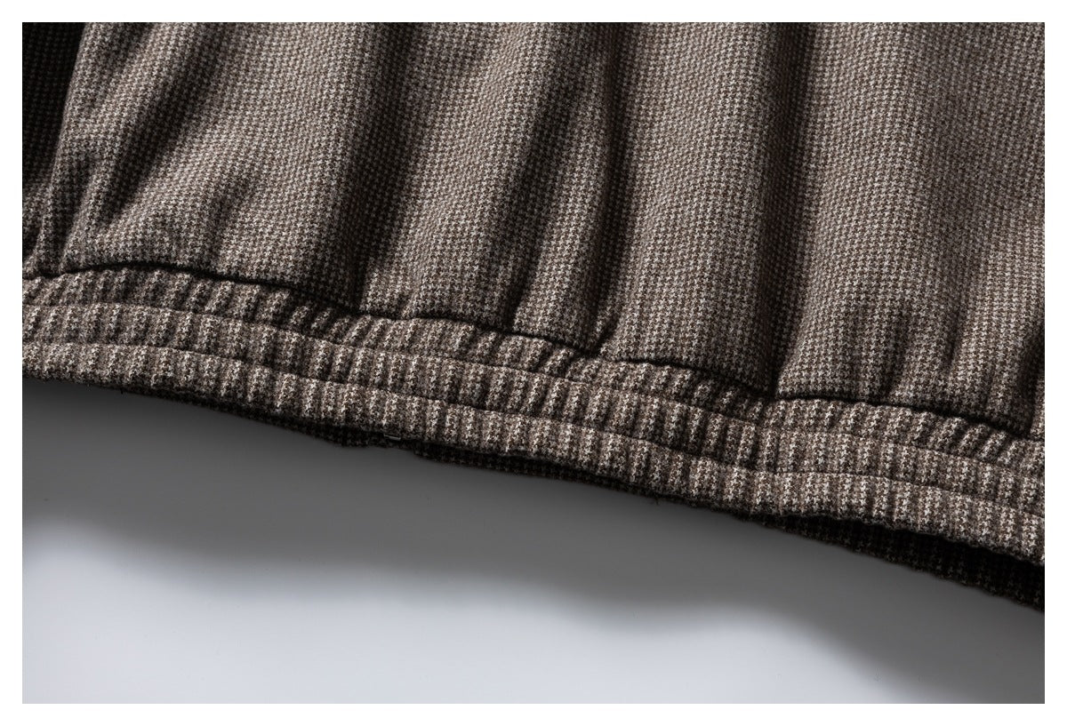 Close-up of the stitched hem on brown and gray houndstooth fabric.