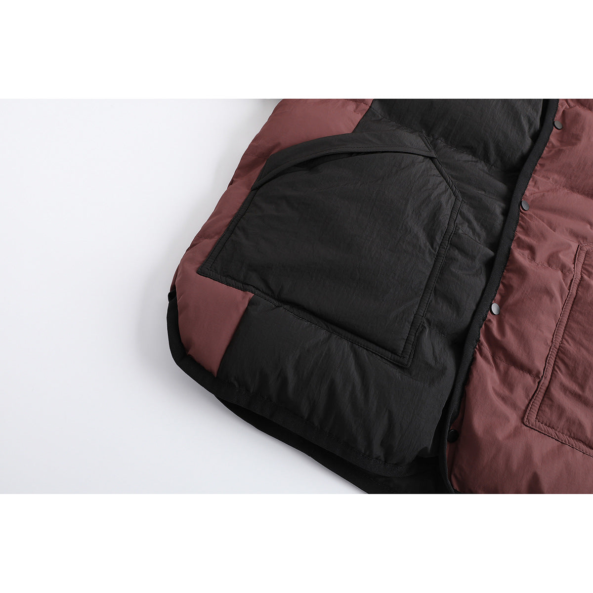 Close-up of the jacket's large black front pocket and burgundy-and-black quilted panels.