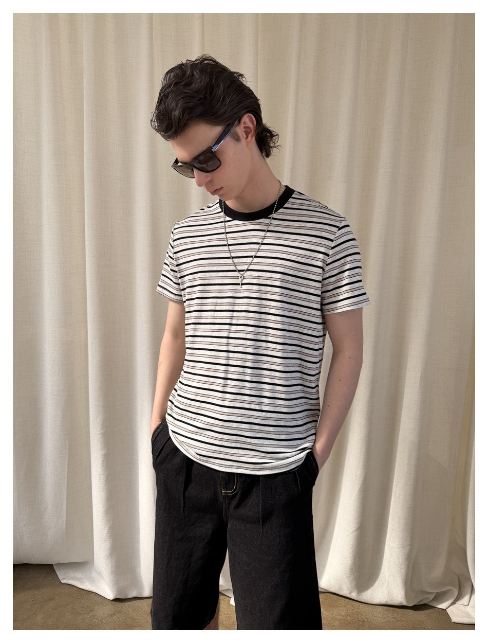 Model wearing a light gray T-shirt with thin black horizontal stripes, black crew neck, and short sleeves.