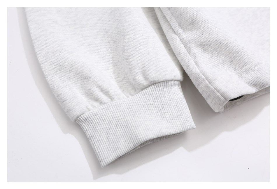 Close-up of a ribbed cuff and sleeve on a light gray heathered garment.