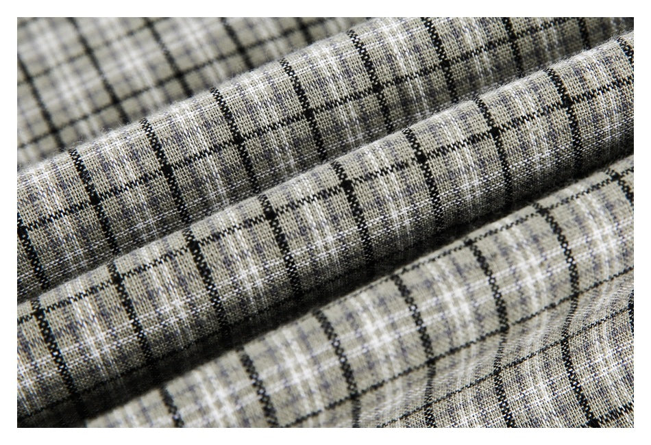 Macro view of folded gray and beige plaid fabric with black grid lines and a visible woven texture.