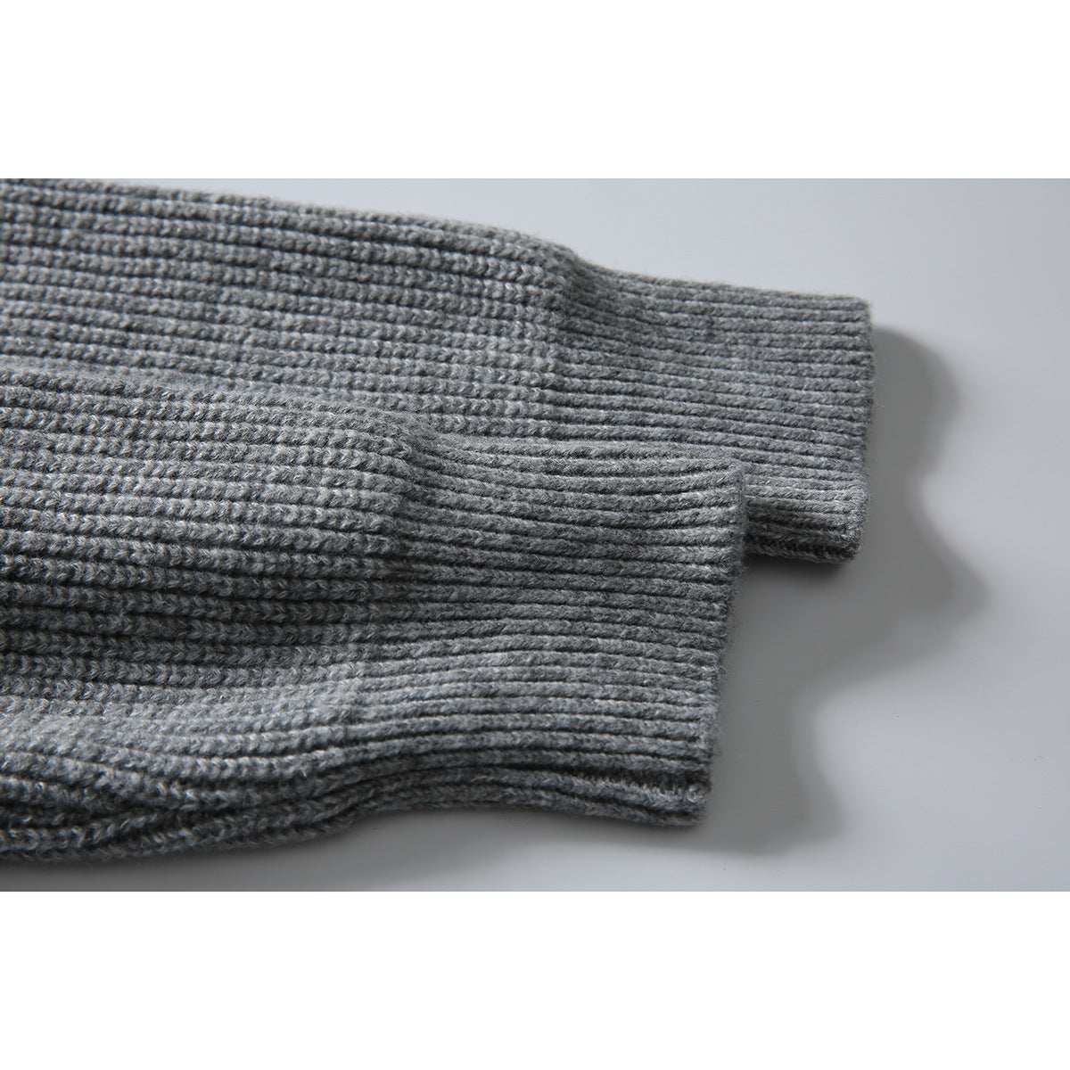 Close-up of a gray rib-knit sweater sleeve and wide ribbed cuff.