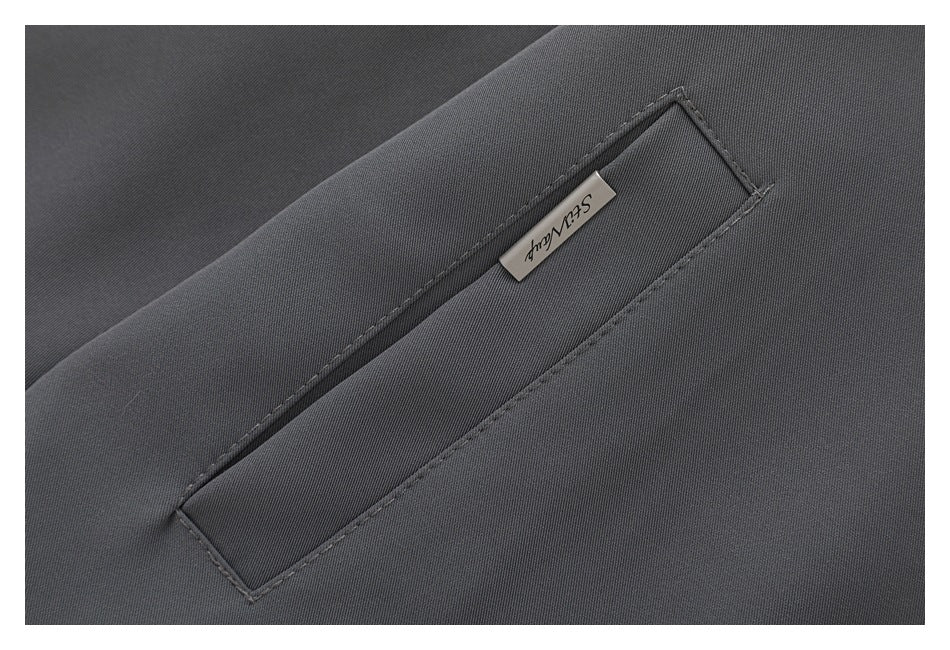 Close-up of a narrow welt pocket and small metal pull on charcoal jacket fabric.