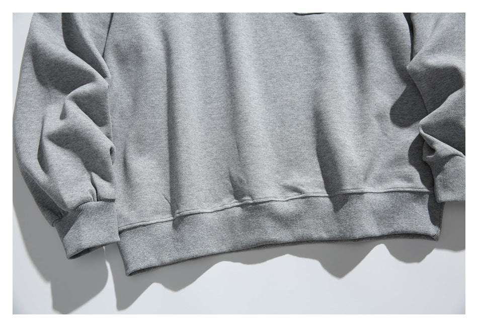 Close view of the lower front of a heather-gray pullover, showing its ribbed hem and sleeve cuffs.