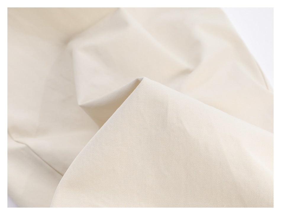 Close-up of the ivory trouser fabric, showing its fine diagonal surface texture.