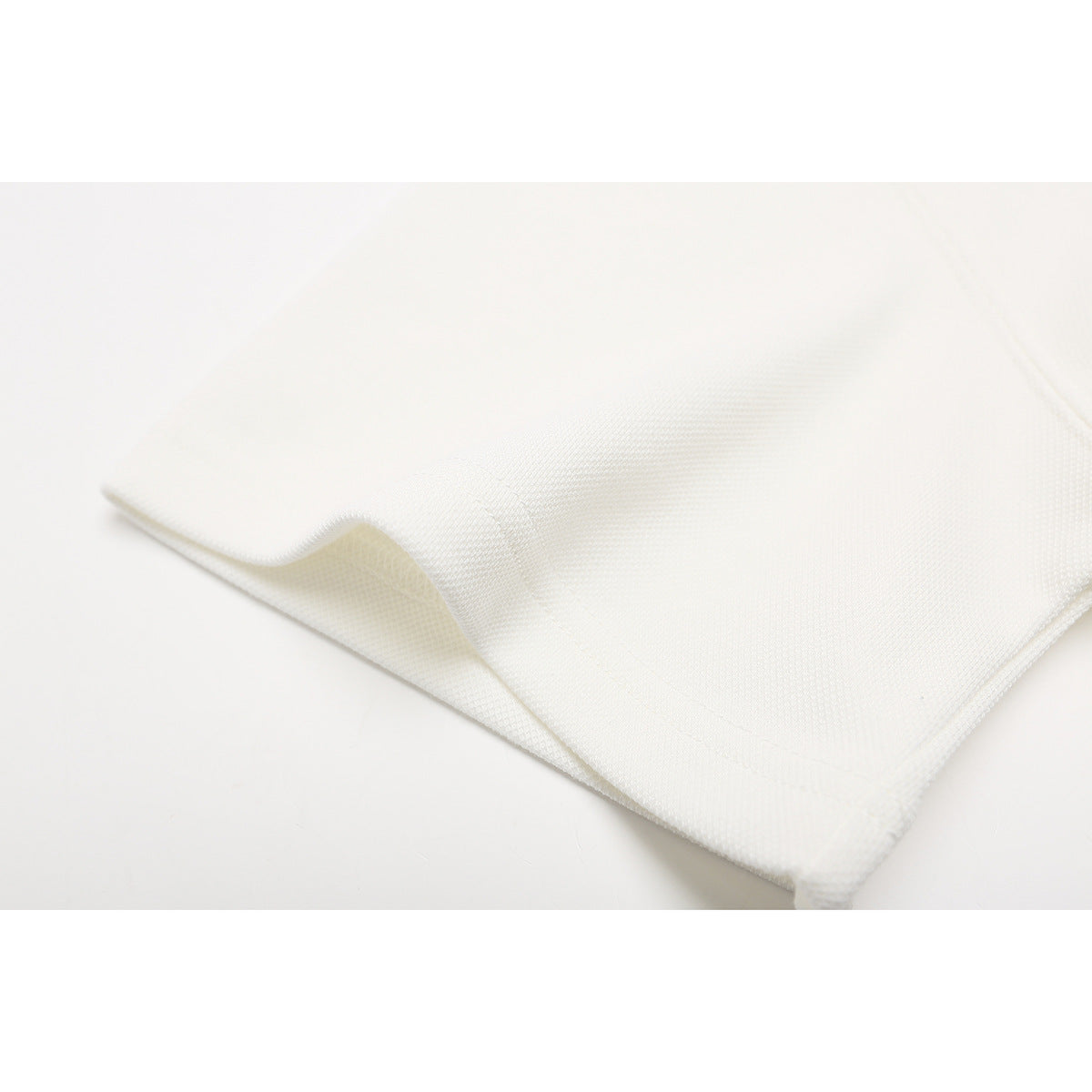 Close-up of the off-white polo shirt fabric and stitched hem.