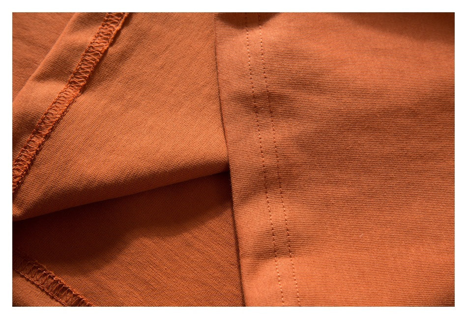 Close-up of orange garment fabric showing an overlocked seam and stitched edge.