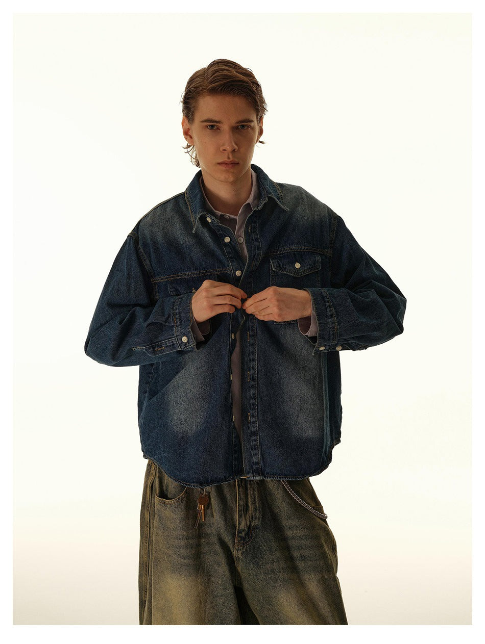 Model wearing a relaxed blue denim shirt over a lilac collared shirt with wide washed pants, buttoning the front