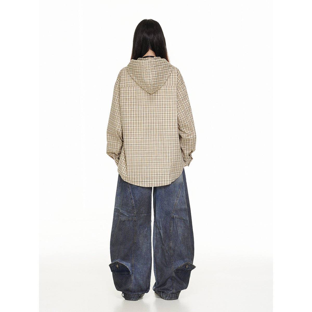 Back view of a model wearing a beige plaid hooded overshirt and wide blue jeans.