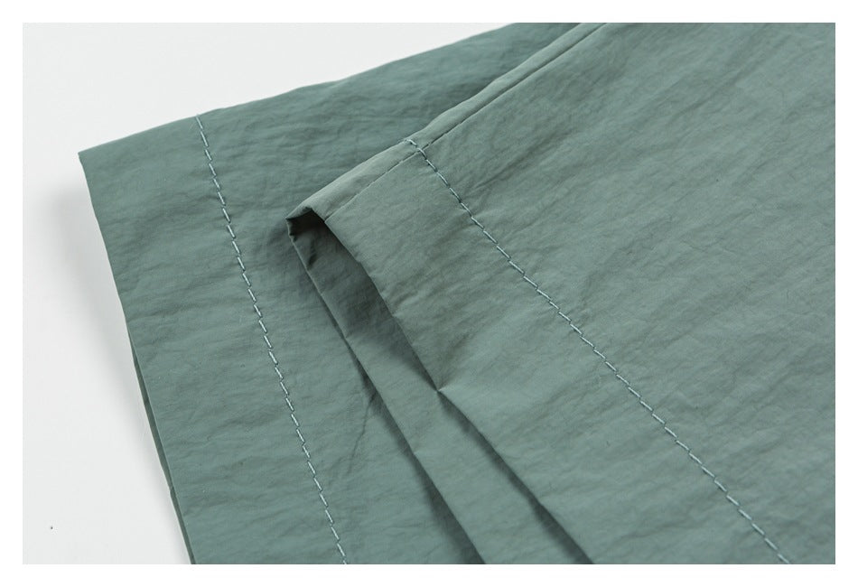 Close-up of the sage green shorts' stitched hem and folded fabric edge.