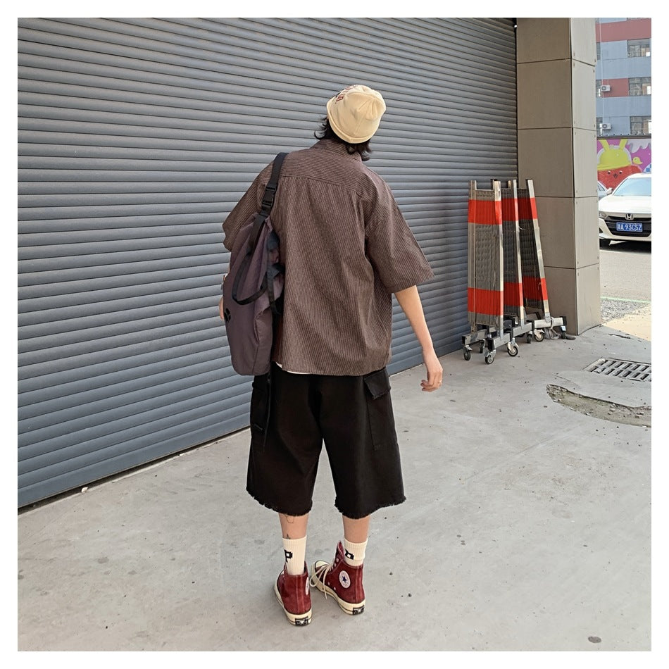 Back view of a person wearing a brown striped short-sleeve shirt with a backpack and black shorts