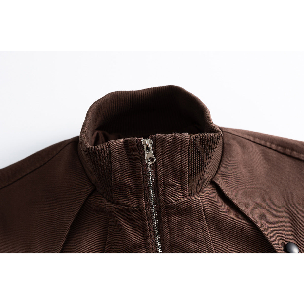 Close-up of a brown jacket’s ribbed stand collar and front zipper.