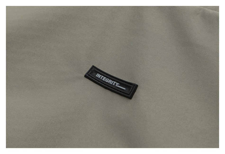 Close-up of an olive-gray garment with a small black INTEGRITY patch.