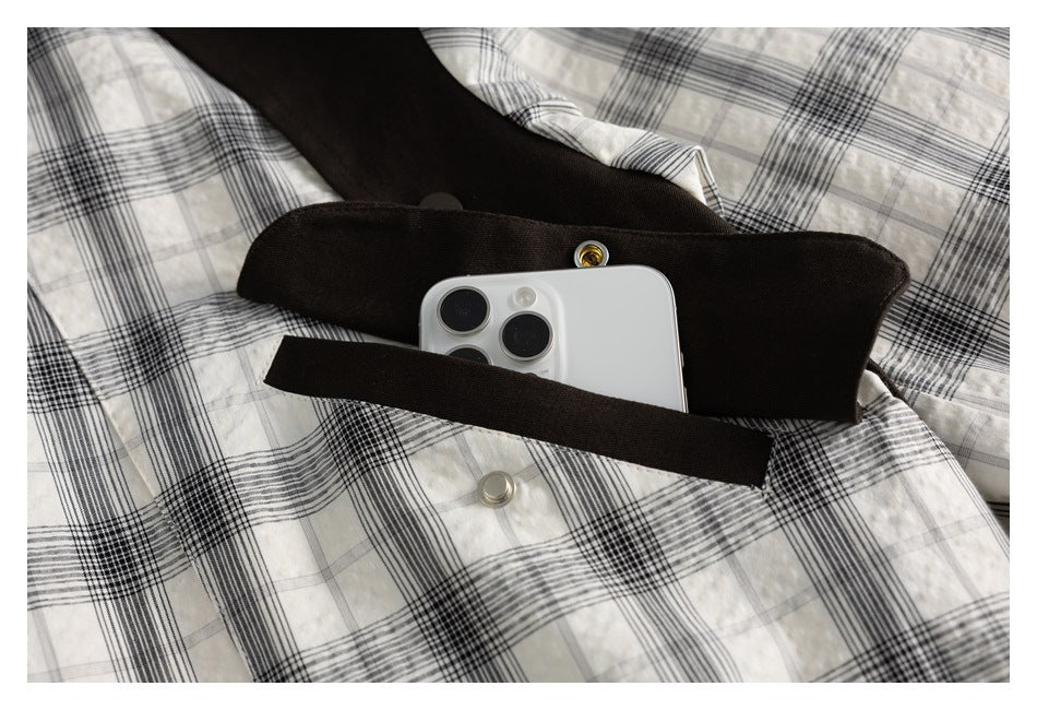 Close-up showing a phone partly inside a dark brown pocket on the black-and-white plaid jacket.