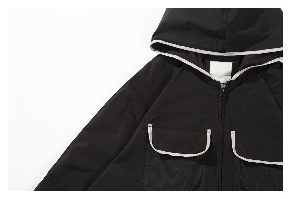 Close-up of a black jacket showing white-trimmed chest pockets, mesh panels, and the front zipper.