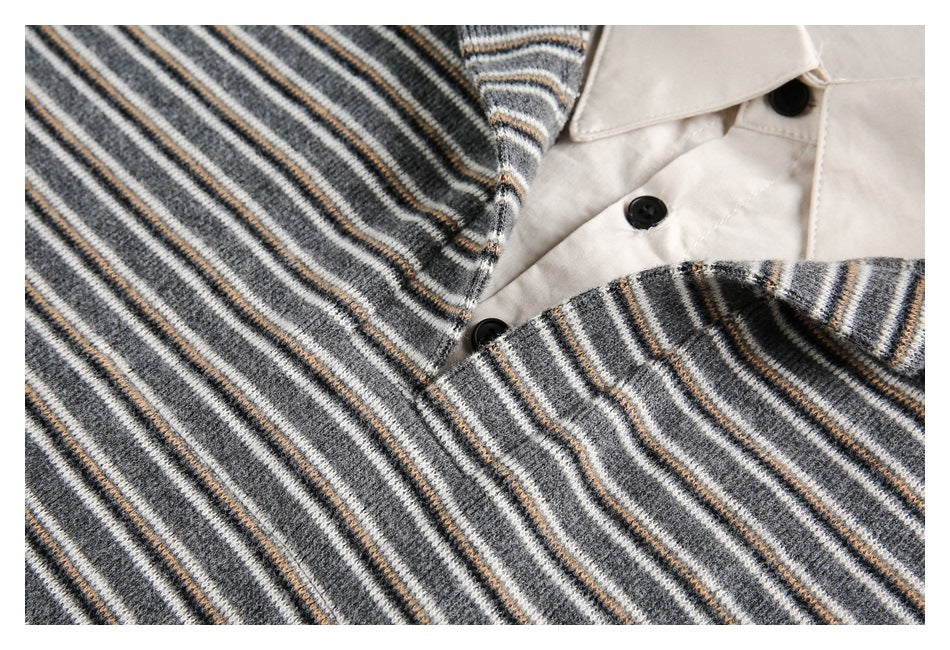 Close-up of a gray striped knit garment opening over a white collared shirt with black buttons.