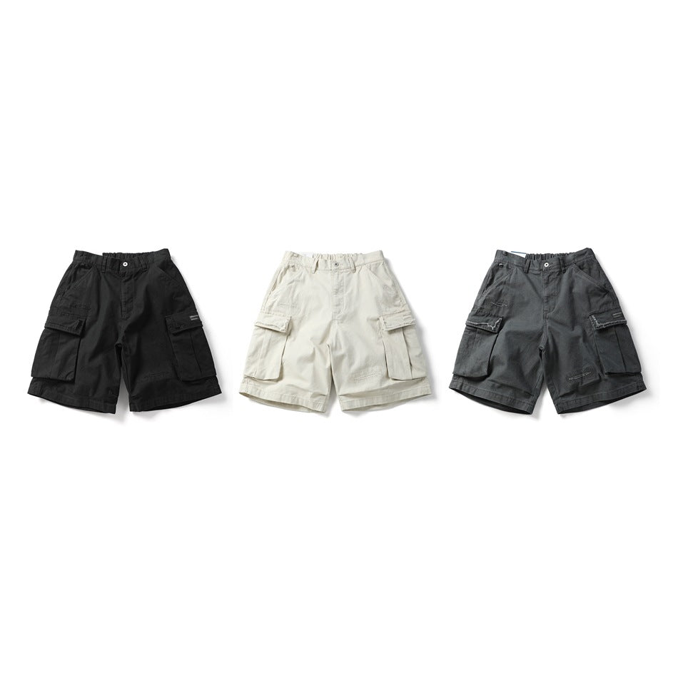 Three front views of cargo shorts in black, off-white and charcoal, each with large side pockets.