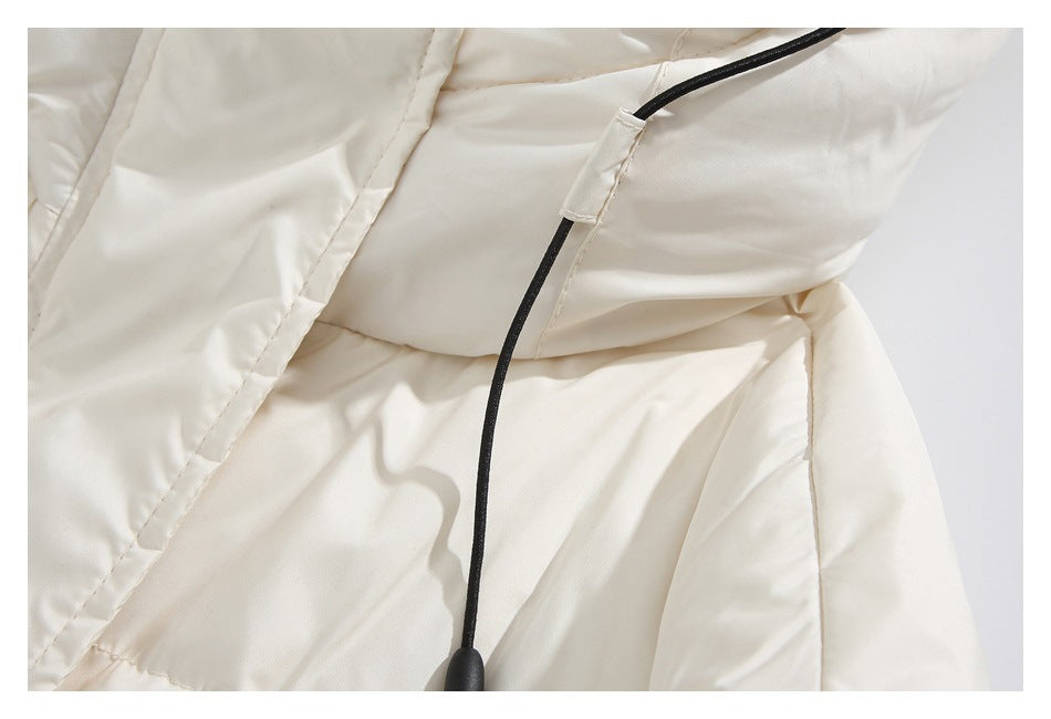 Close-up of the ivory coat's black hood drawcord and toggle against the quilted fabric.