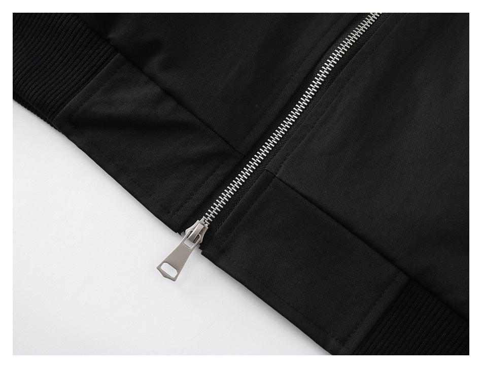 Close-up of the silver front zipper, ribbed cuff and lower hem of the dark jacket.