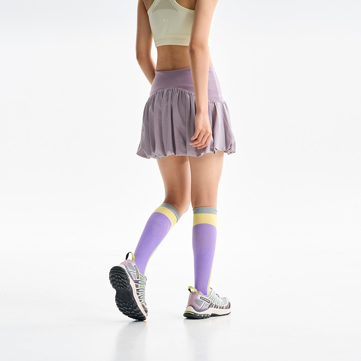 Side and back view of a model wearing a lavender bubble skirt with a wide waistband.