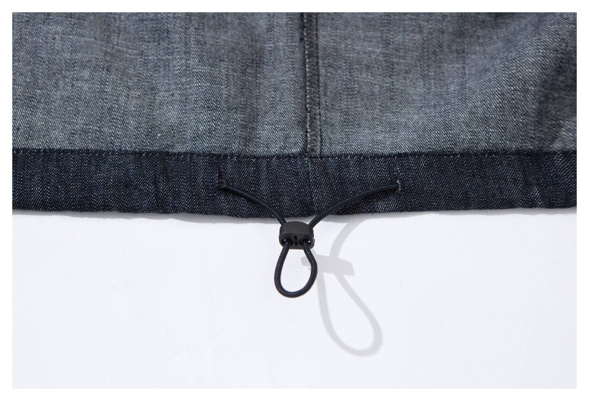 Close-up of a dark indigo jacket hem with an adjustable elastic drawcord and toggle.
