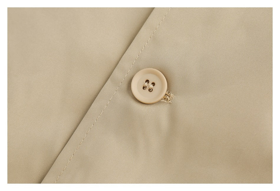 Close-up of a beige coat button and stitched buttonhole beside a diagonal seam.