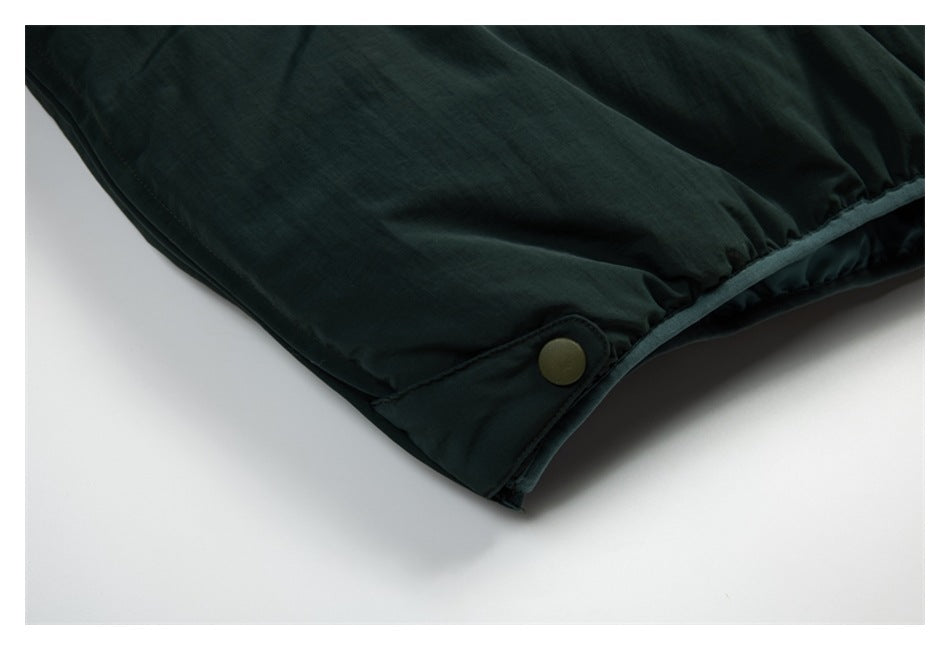 Close-up of the dark green jacket's hem with an adjustable snap tab and gathered edge.