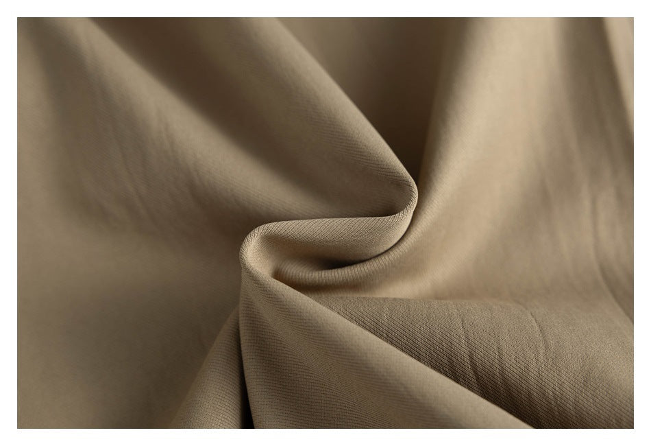 Close-up of khaki fabric draped into soft folds, showing its fine surface texture.