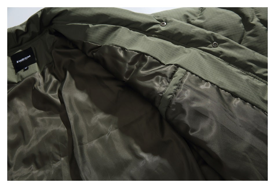 Interior view of an olive quilted jacket showing its dark lining, snap placket, and sewn-in label.