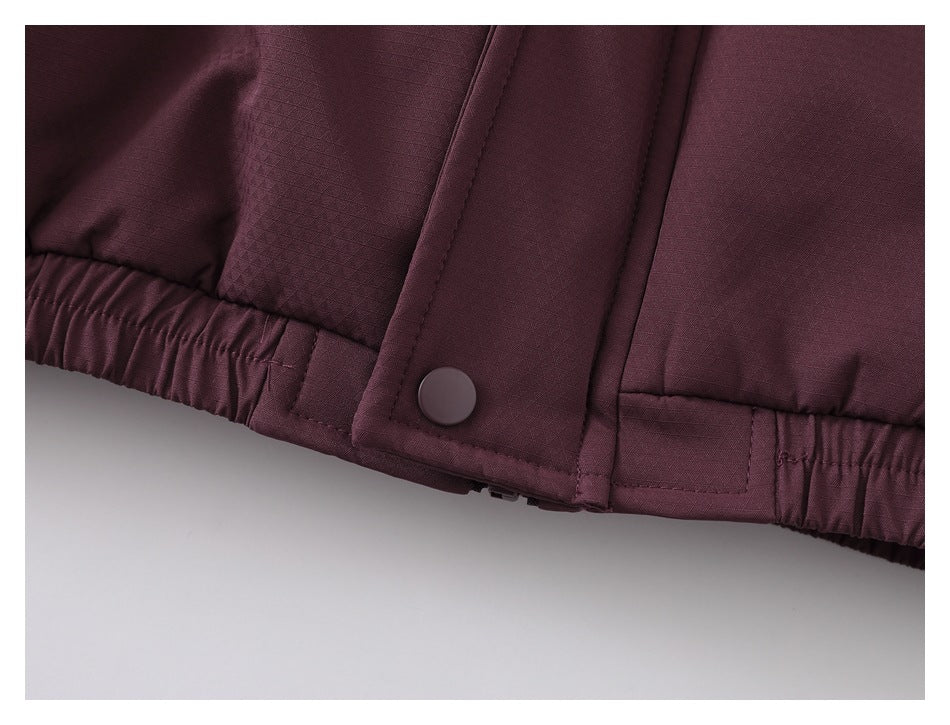 Close-up of the burgundy jacket hem showing an elasticized edge and a snap-fastened placket.