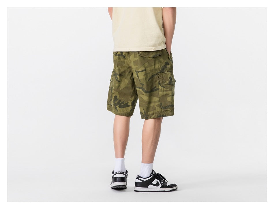 Model wearing olive camouflage cargo shorts, shown from the back with a side pocket visible.