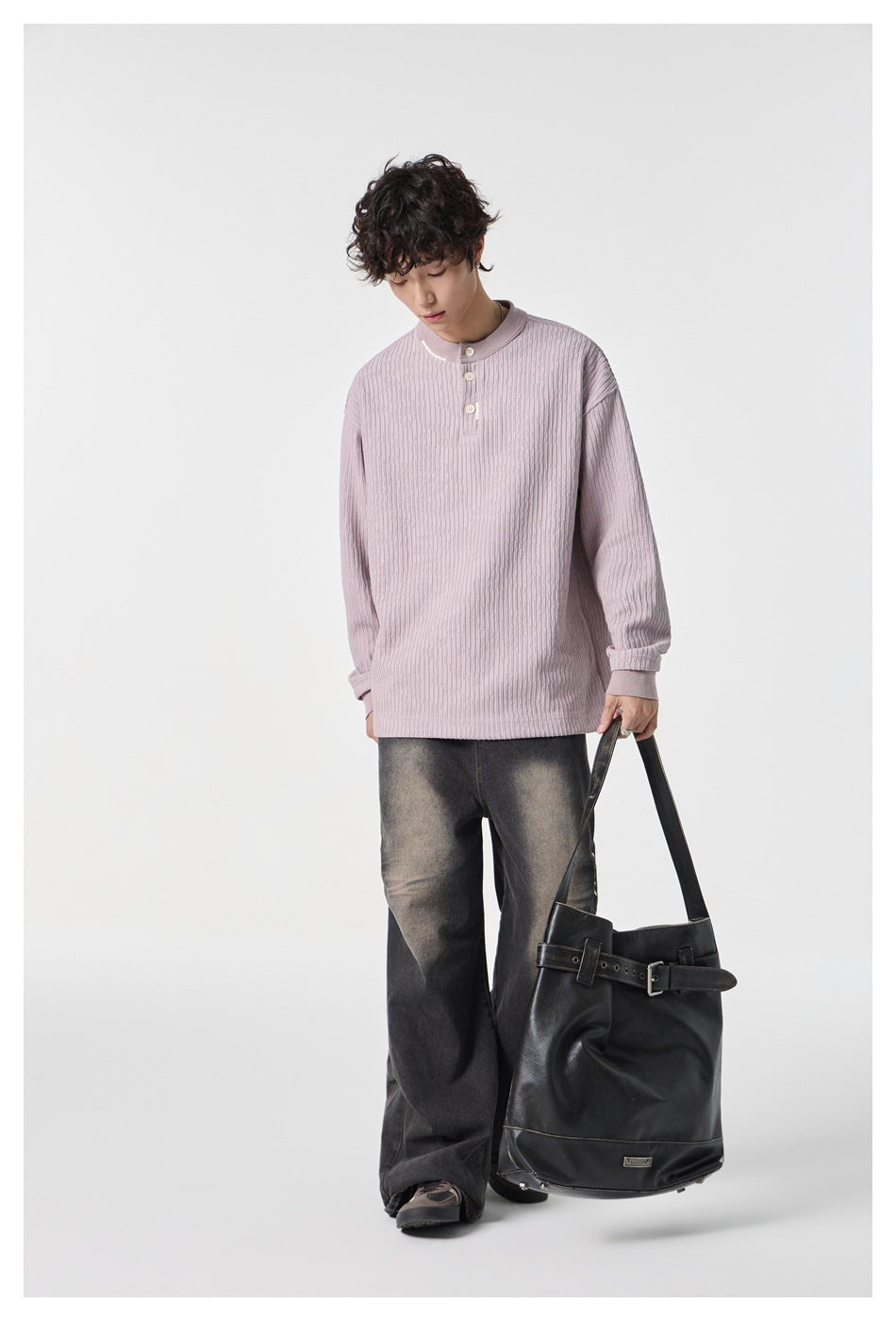 Model wearing a pale pink textured three-button top with dark washed wide-leg jeans and carrying a black tote.