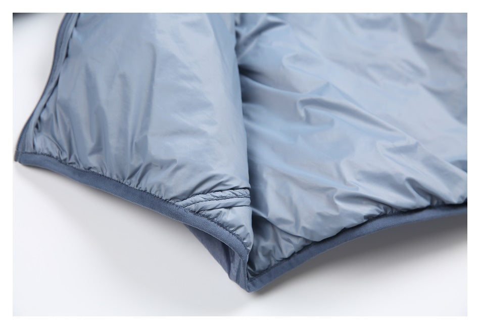 Close-up of light blue padded fabric with stitched seams and dark blue bound edging.