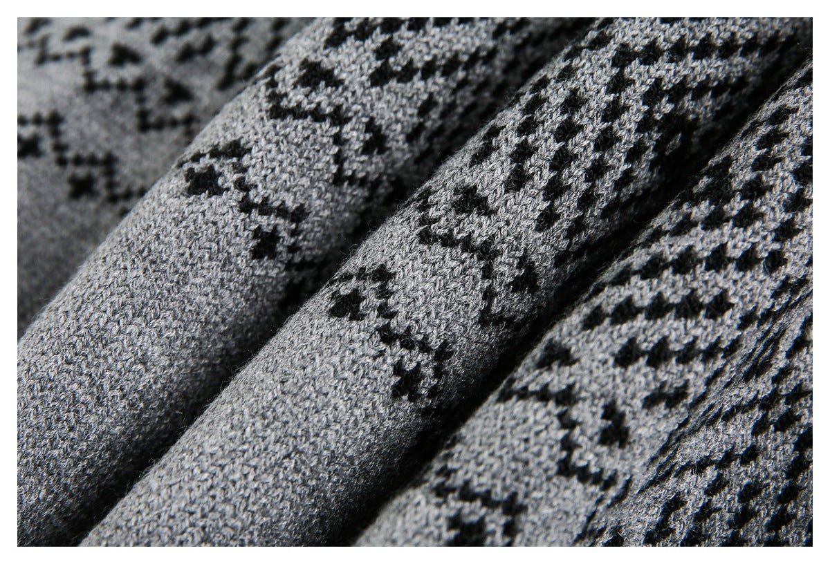Macro view of gray knit fabric with black geometric motifs and visible stitches.