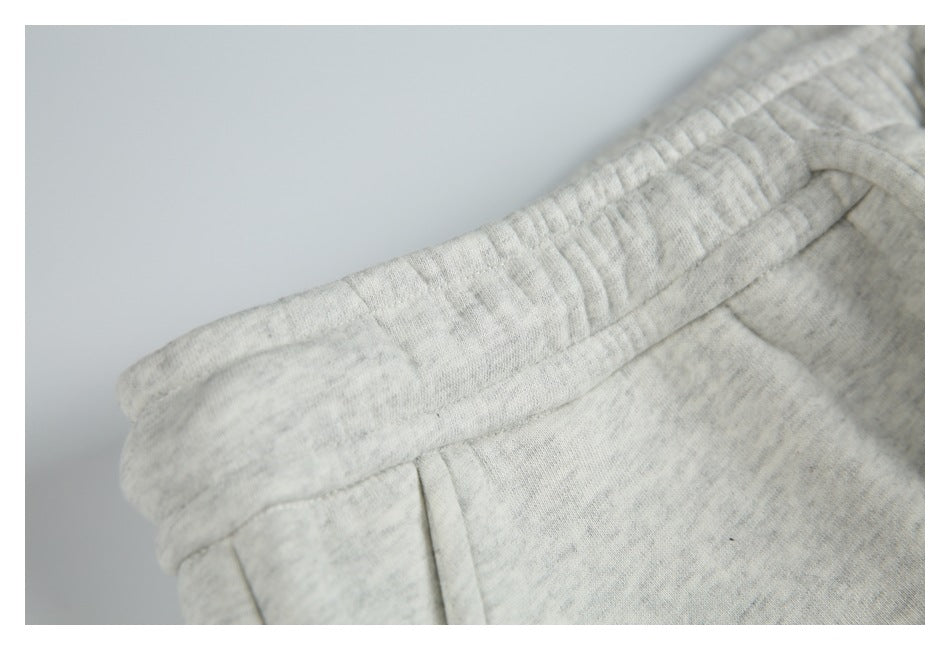 Close-up of the gathered elastic waistband and pocket seam on light gray marl sweatpants.