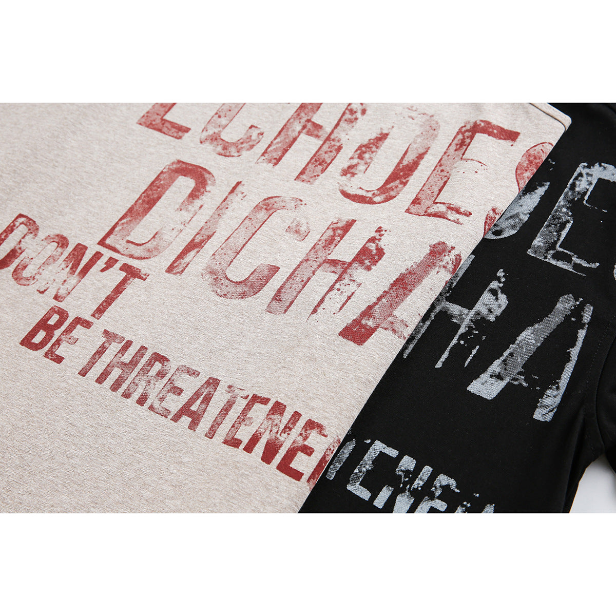Close-up of distressed lettering on beige and black T-shirts, including the phrase “DON'T BE THREATENED.”