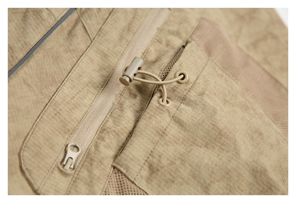 Close-up of a tan trouser pocket with a zipper and cord adjuster.