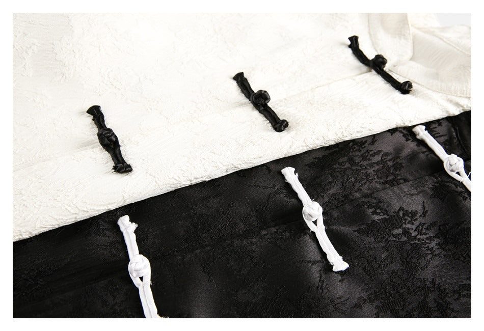Close-up of ivory and black tops with contrasting knotted frog closures and patterned fabric.