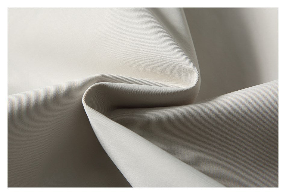 Close-up of light beige fabric folded into a soft curve, showing its fine surface texture.