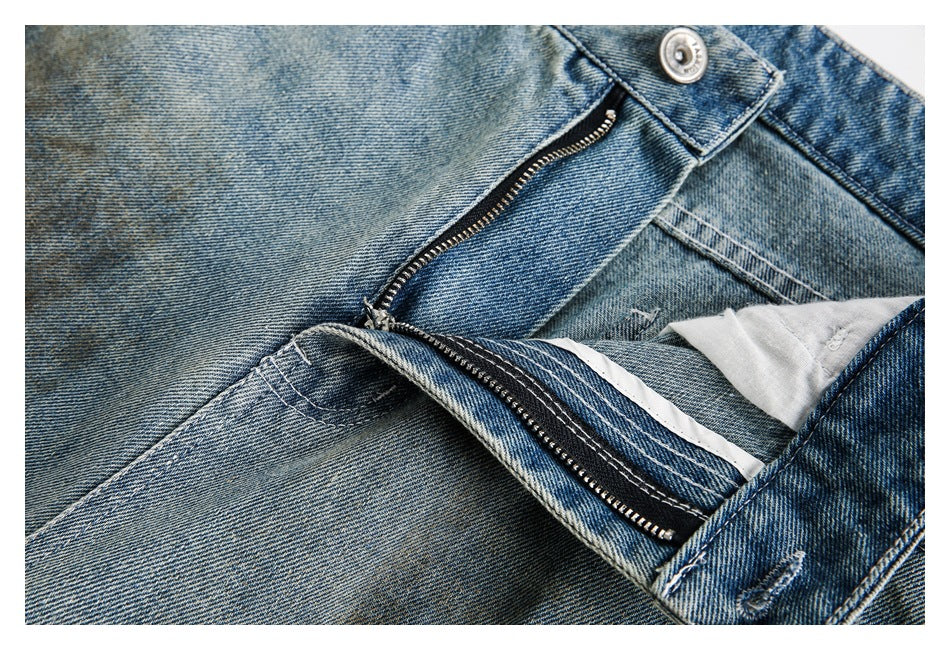 Close-up of light blue faded jeans with the metal-button waistband and zip fly open.