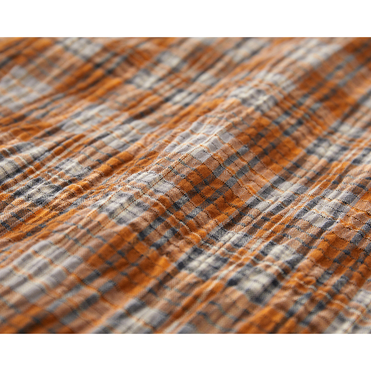 Close-up showing the textured orange, gray, and cream plaid shirt fabric.