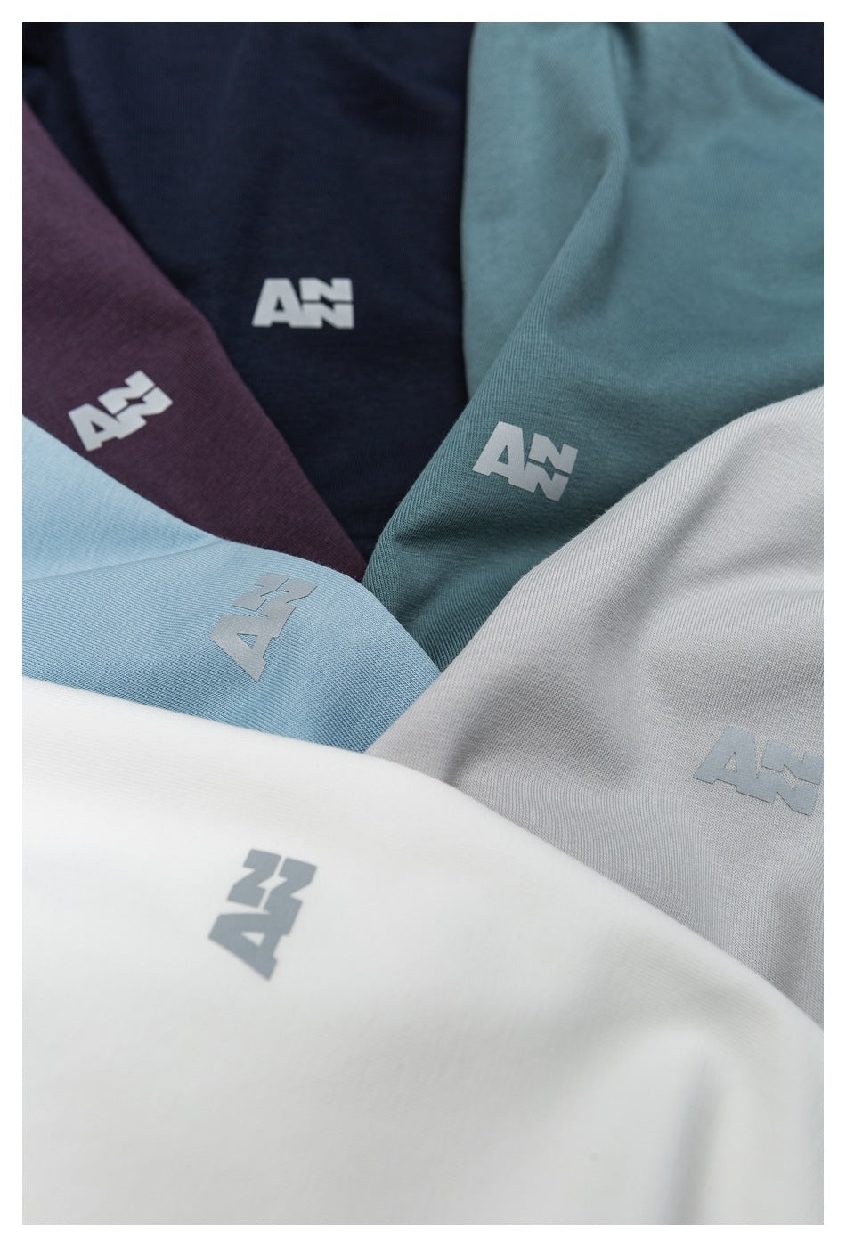 Teal, navy, plum, light blue, gray, and white garments arranged together, each with a small logo.