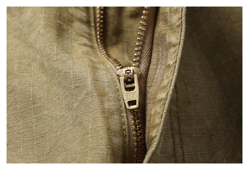 Extreme close-up of the metal zipper and textured tan fabric on the pants.