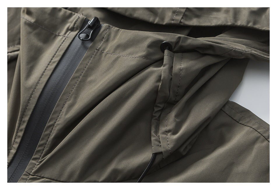 Close-up of the olive-gray jacket's front zipper and adjustable hood drawcord.
